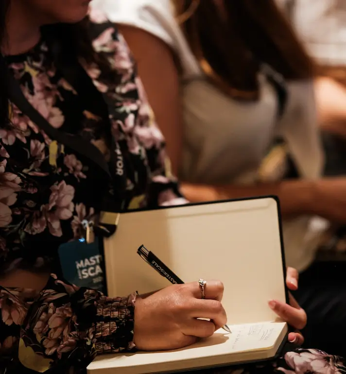 Participante do Master and Scale a tomar notas num caderno durante uma palestra